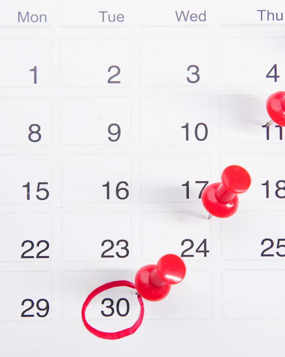 close up photo of red pins on a calendar