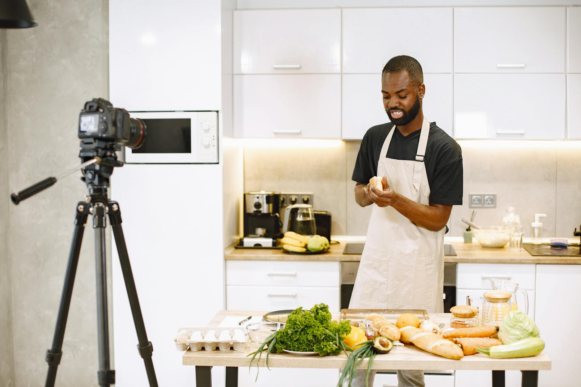 male vlogger in white apron slicing a bread