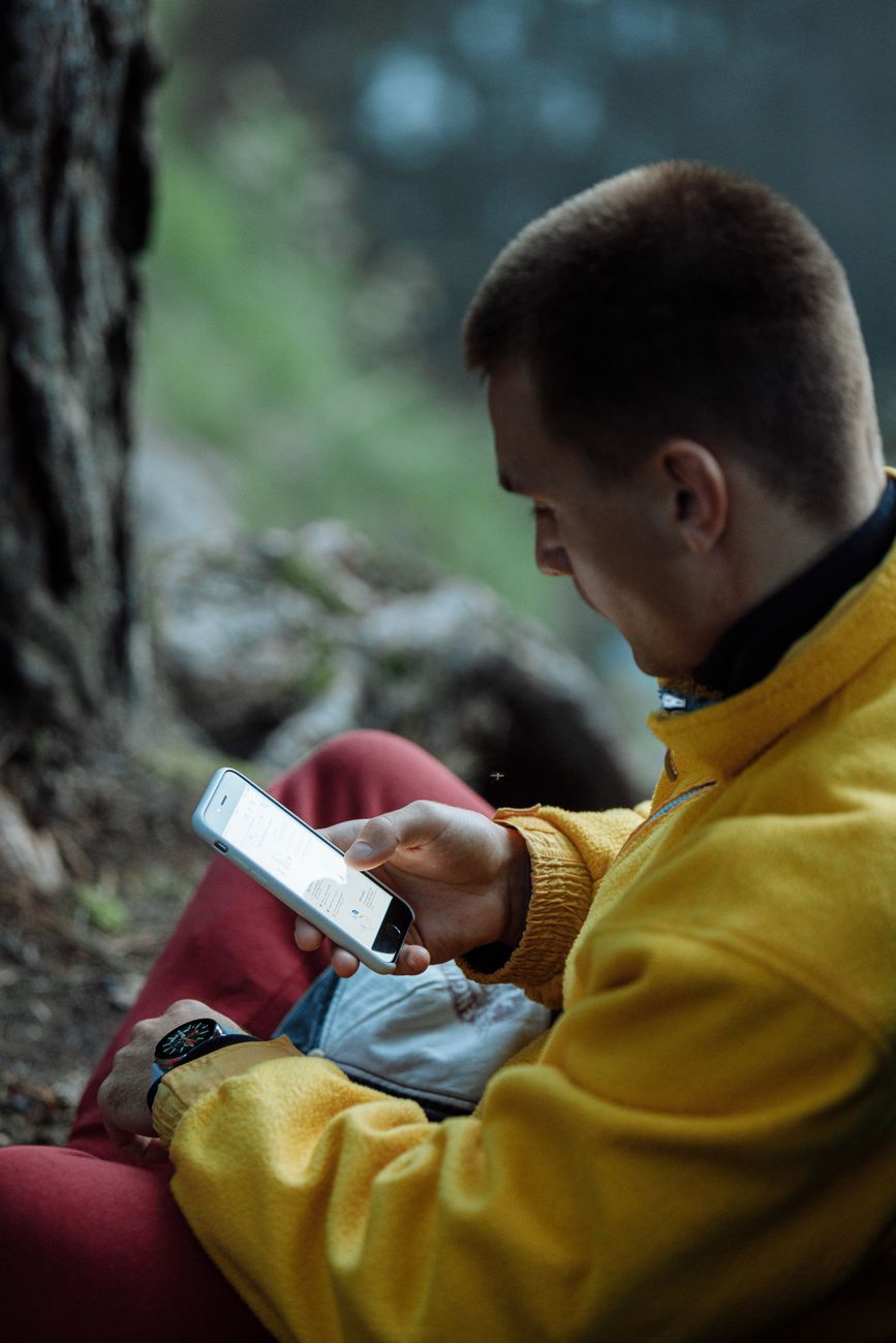 man in yellow jacket holding his phone
