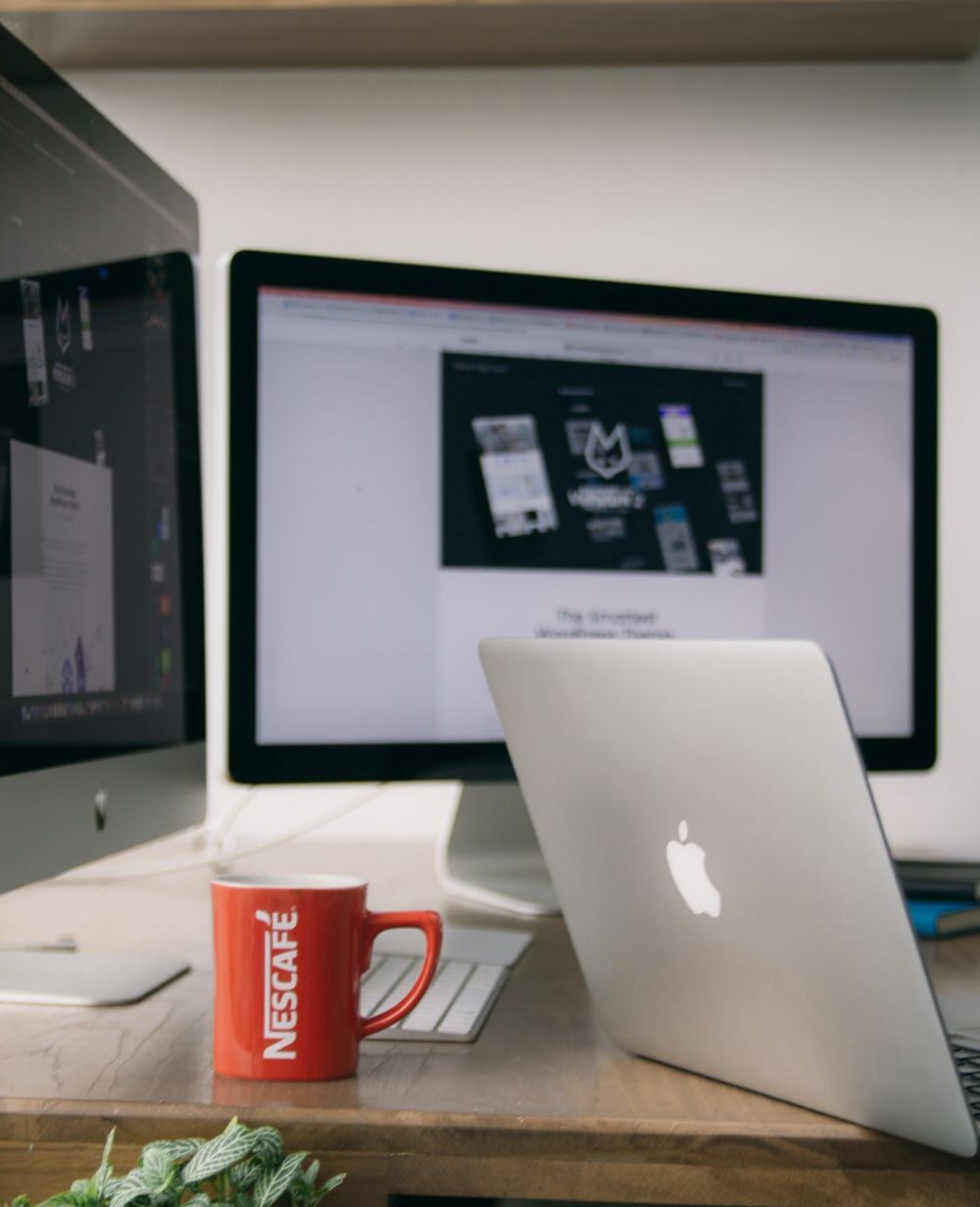 silver macbook on top of brown wooden table